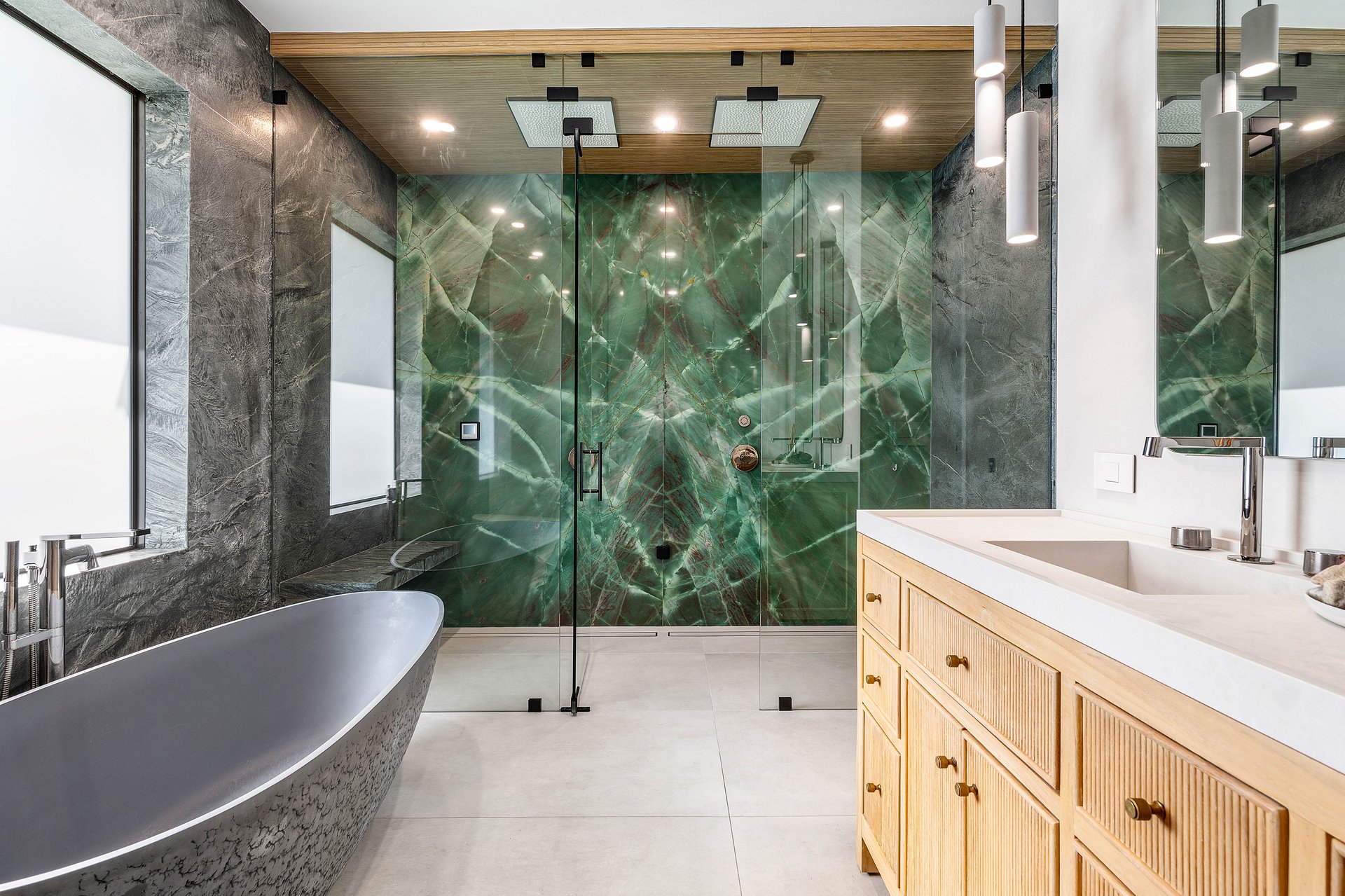Master bath with book-matched green marble steam shower and stone freestanding soaking tub